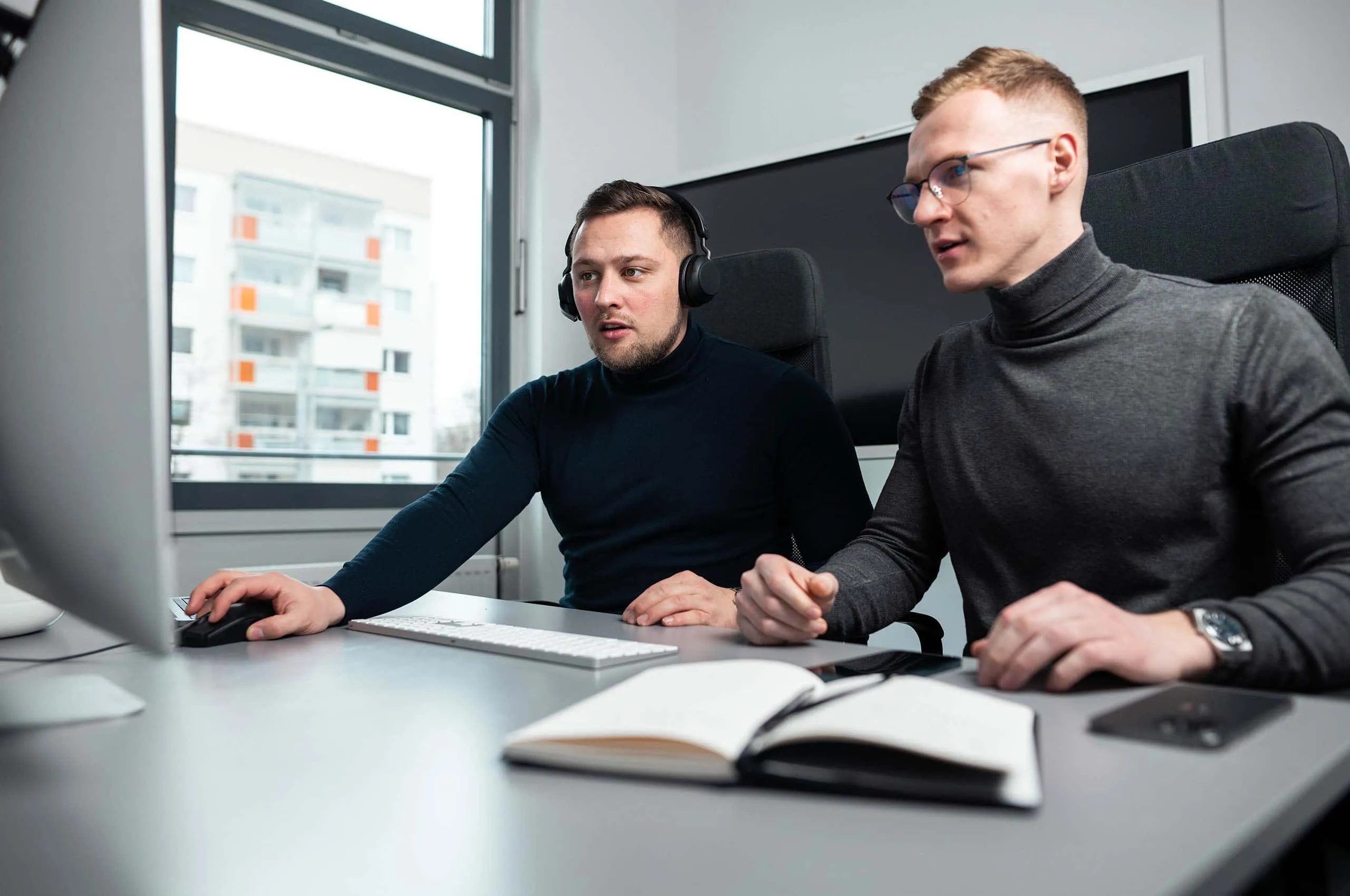 Zwei Männer arbeiten zusammen an einem Computer während eines Vertriebscoachings.